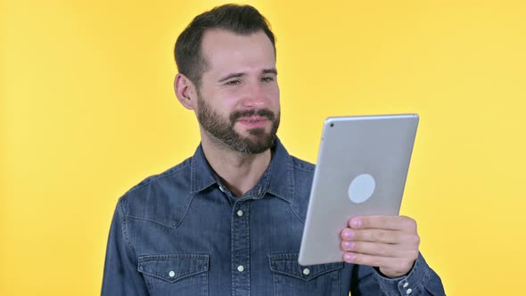 Beard Young Man Doing Video Chat on Tablet, Yellow Background