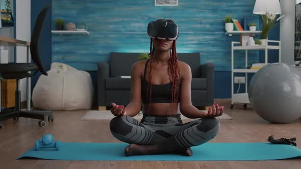 Fit Black Woman Wearing Virtual Reality Headset While Sitting on Yoga Map