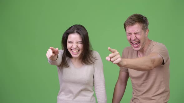 Young Happy Couple Laughing and Pointing Finger Together