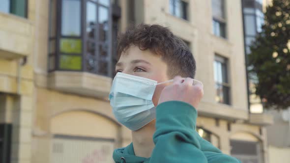 A young man puts on and adjusts a medical mask