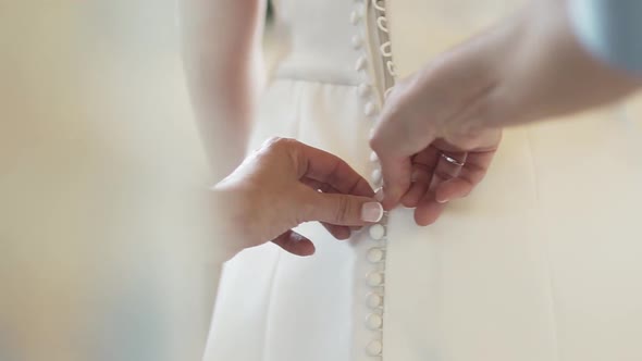 Person hands buttoning corsage on bride