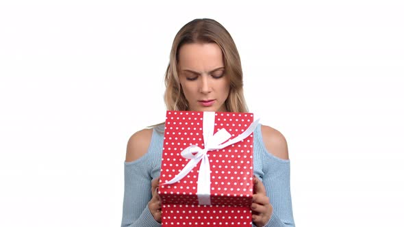 Portrait Blonde Woman Opening Wrapped Festive Gift Box with Bad Surprise Posing Isolated on White