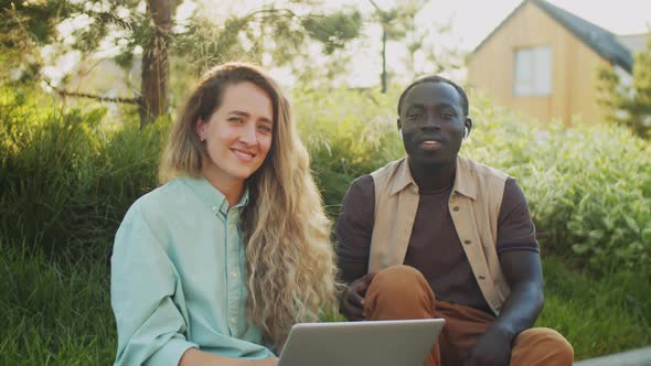 Portrait of Positive Black Man and Caucasian Woman with Laptop on Street