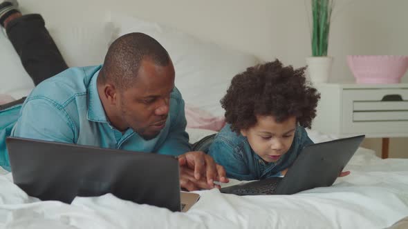 Caring Black Dad Teaching Son Using Laptop at Home