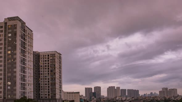 Day to night time lapse in densely populated urban area with artificial electric lights coming on in