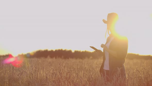 A Farmer Girl with a Tablet Computer in Her Hands Examines the Ears of Rye and Enters Data Into the