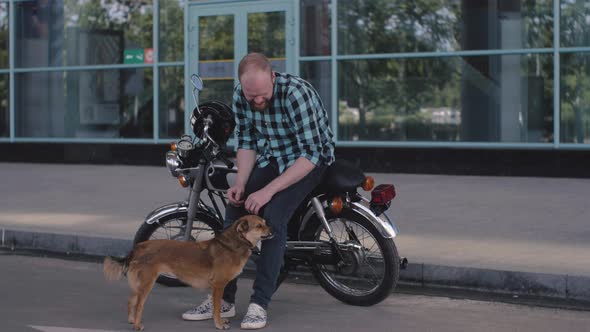 Male Motorcyclist with a Stray Dog on the Street