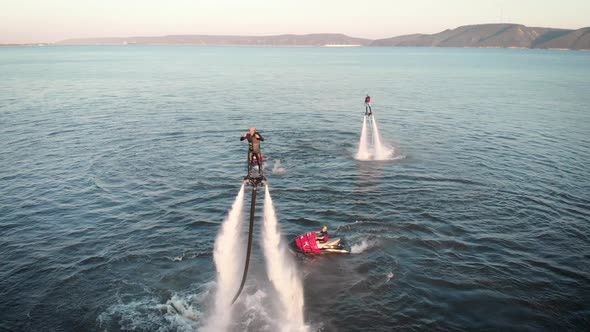 Cheerful Male Flyboarder Is Flying Over Sea Surface and Posing for Aerocamera in Air in Daytime