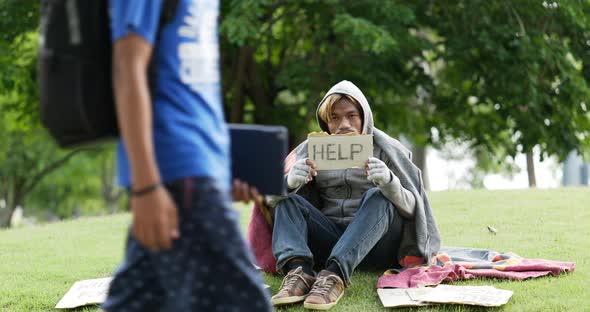 Homeless man sitting and holding help sign