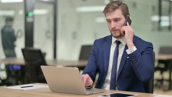 Businessman with Laptop Talking on Phone