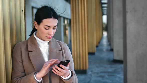 Pensive Woman Use Smartphone Chatting at City Building Exterior