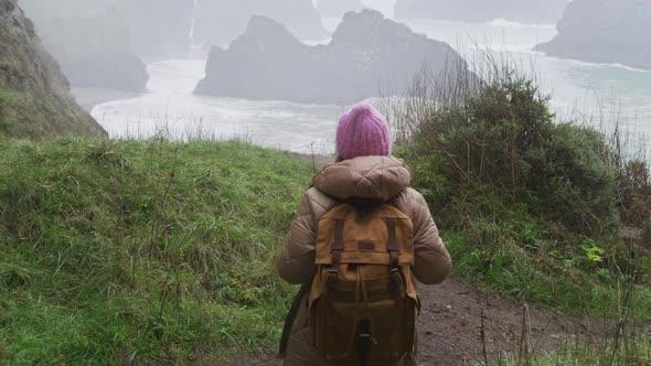 Tourist Female Relaxing and Looking at Stormy Ocean Beach with Scenic Rocks USA