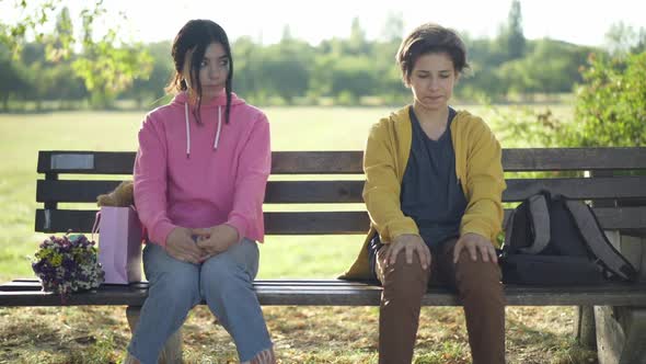 Front View Shy Unsure Teenage Couple Sitting on Bench Thinking Looking Around