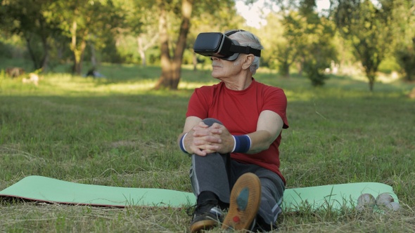 Elderly Man in VR Headset Helmet Sitting on Sport Mat. Online Sport Workout for Senior People