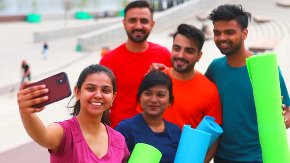 Four Indian People Warming Up Outdoors in Sport Wear Making Selfie on Smartphone Camera