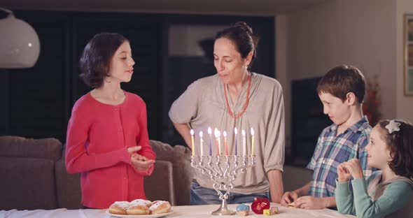 Kids and their mother lighting Hanukka candles