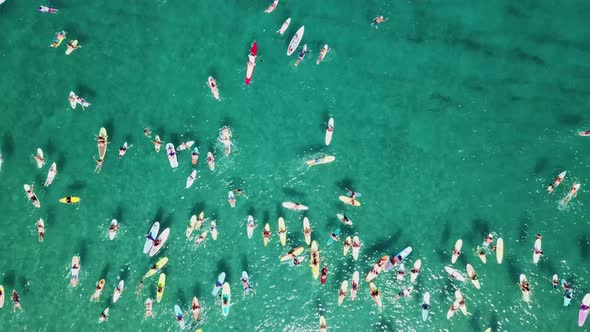 Cool overhead zoom-in shot of a group of paddle boarders paddling out in the Atlantic ocean.