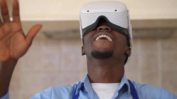 Closeup Front View Carefree African American Man in VR Headset Gaming Online Standing in Kitchen