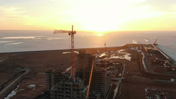 Flying Around a Construction Crane and Construction Site at Sunset, Shooting From a Drone