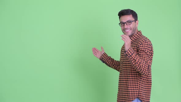 Happy Young Hispanic Hipster Man Presenting Something To the Back