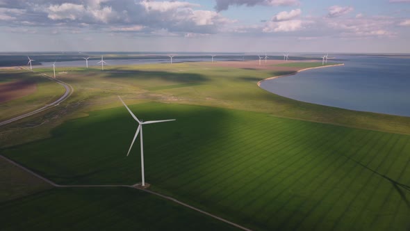 Aerial View of Wind Turbines and Agriculture Field Near the Sea at Sunset