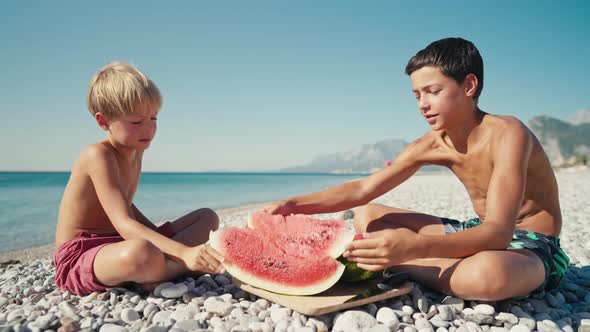 Happy Kids Eating Big Red Slices of Watermelon on the Beach