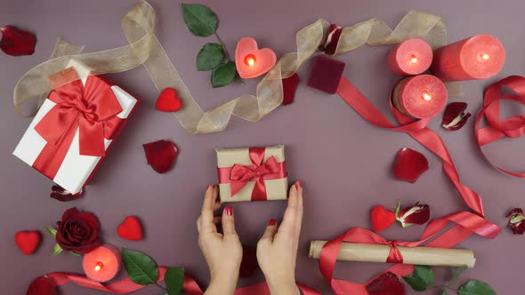 Hands put wrapped gift box with tied red ribbon bow for St. Valentine's Day