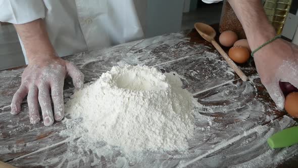 Chef Cracking an Egg Into Flour to Make Bread According to Traditional Recipe