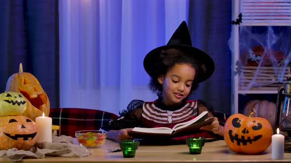 Little African American Girl in Festive Costume Reads Book with Enthusiasm