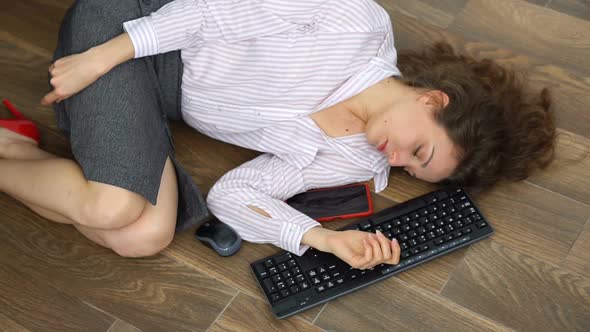 Tired Young Female Office Manager is Lying on the Floor with Keyboard Mouse and Smartphone Lay Flat