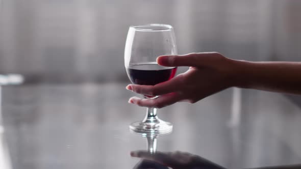 A Glass of Red Wine Stands on the Table a Woman Hand Takes a Glass