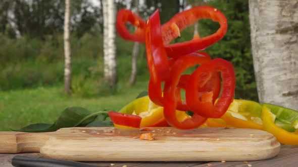 Slices of Fresh Ripe Pepper Falling on a Wooden Board in Slow Motion