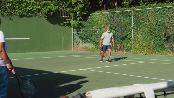 African american senior couple playing tennis on the tennis court on a bright sunny day