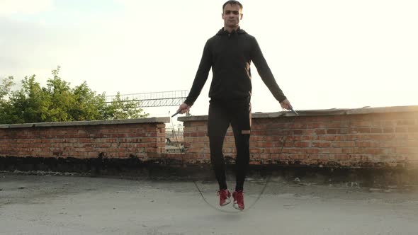 Sporty man jumping with rope training outdoors. man uses  skipping rope on roof