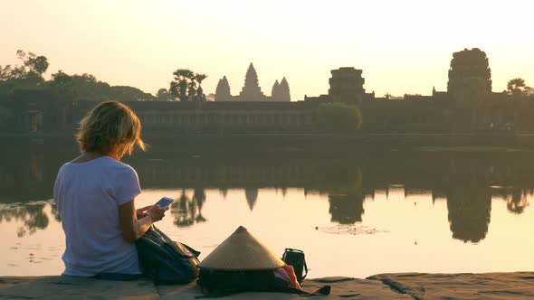 Woman using smart phone at Angkor Wat ruins, famous tourist destination Cambodia