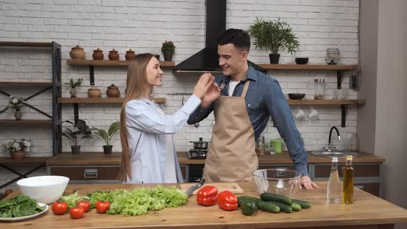 Cooking Salad at Home Young Woman and Man Meeting and Giving High Five in Modern Kitchen