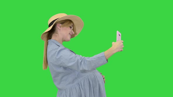 Charming Pregnant Woman in a Hat Making Selfie on a Green Screen, Chroma Key