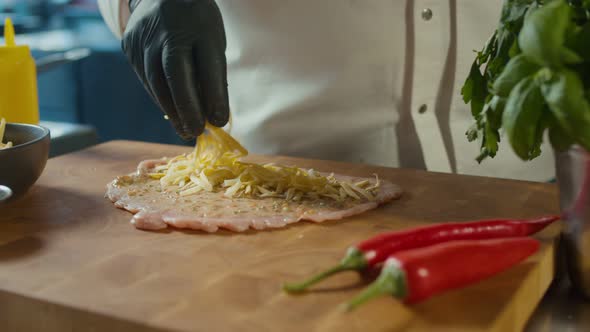 Close Up Professional Chef Sprinkling Cheese on a Raw Pork Chop