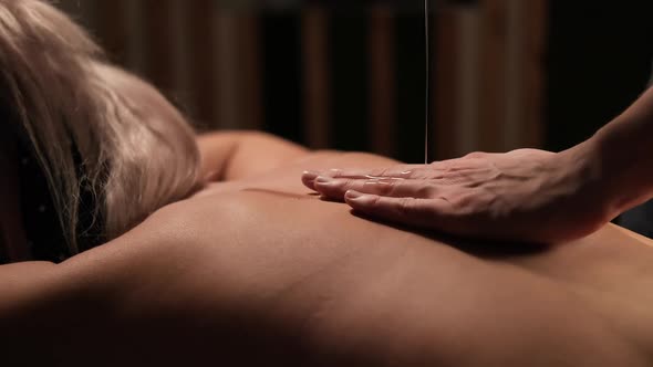 Masseur Hands Pouring Massaging Oil to Female Back Preparing to Massage