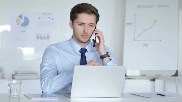 Angry Young Businessman Talking on Phone