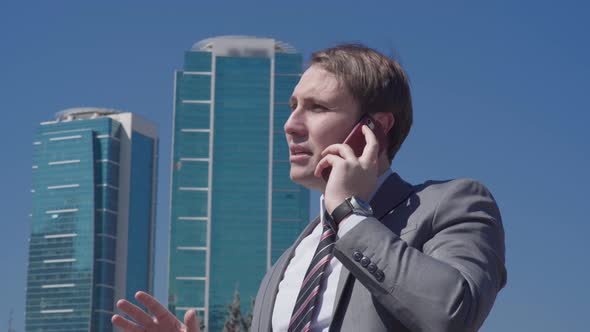 Businessman talking on the phone in front of business buildings.