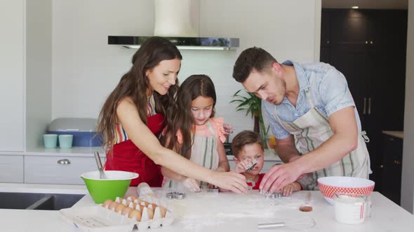 Happy caucasian family baking together, preparing cookies in kitchen