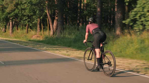 Woman intensively pushing pedals on bicycle. Cyclist twists pedals on bike, sprinting out of saddle