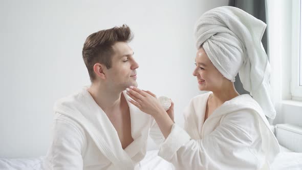 Tender Woman Takes Care of Man's Skin Applying Moisturizing Cream on Face Enjoy Beauty Procedures