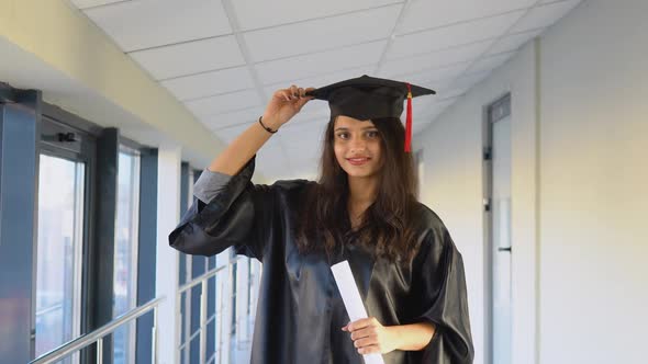 Indian Female Graduate in Mantle Stands with a Diploma in Her Hands and Smiles