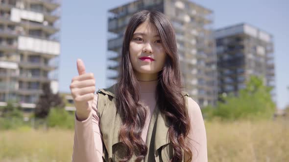 Young Asian Woman Shows Thumb Up To Camera Nods Smile  Apartment Building