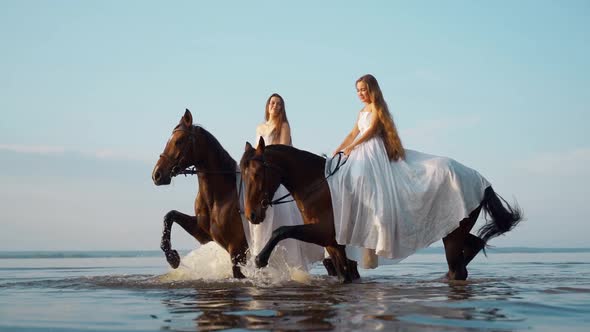 Two Beautiful Girls in White Long Dresses on Horseback