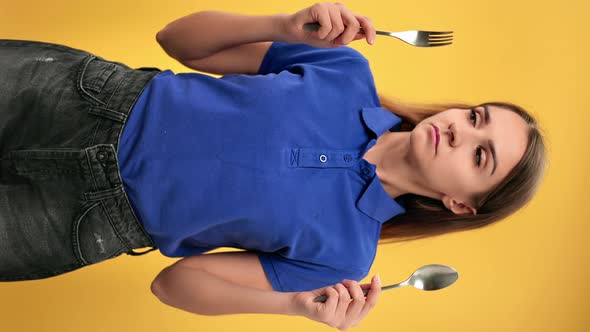 VERTICAL VIDEO POV Unhappy Woman on Diet Choosing Between Fork and Spoon with Hungry Face Expression