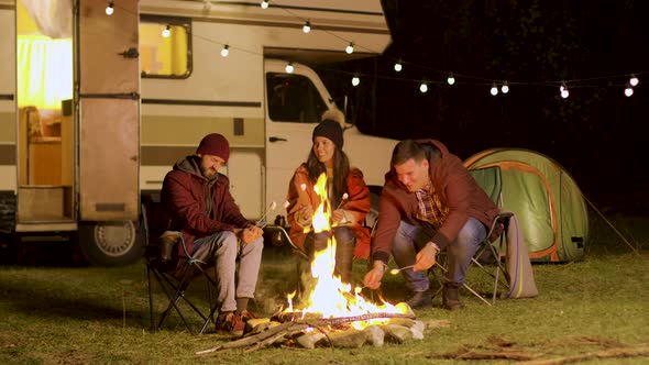 Group of Happy Friends Around Burning Camping Fire