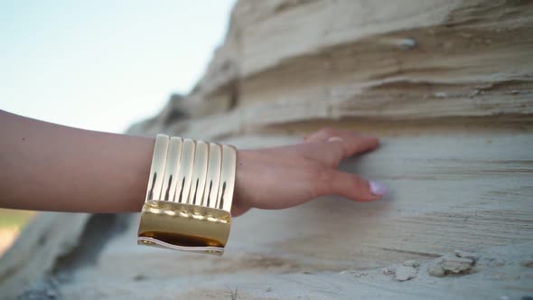 Female Hand with an Oriental Gold Bracelet on a Background Sand